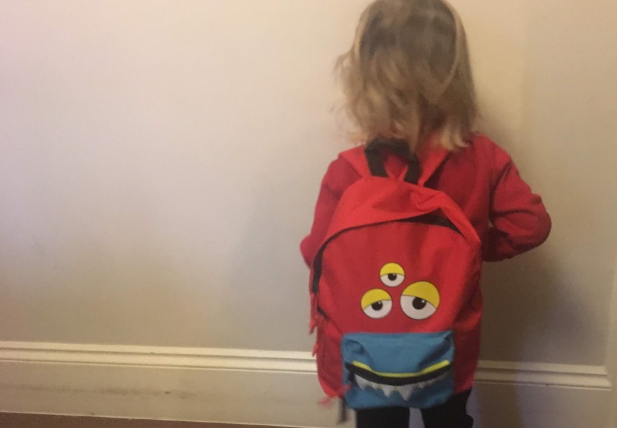 Child in school uniform wearing a monster backpack